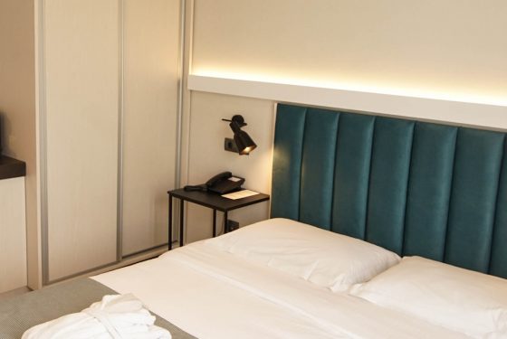 Side view of the double bed, neatly folded bathrobes on the bed and wardrobes in the Standard Room Single/Double