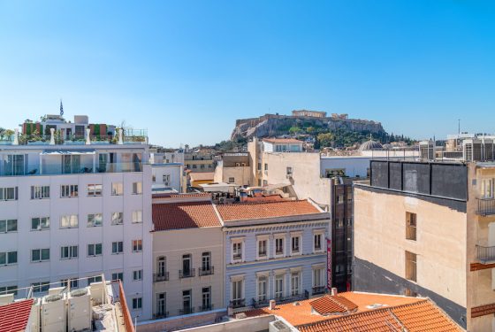 A view of city buildings and the Acropolis in the distance.