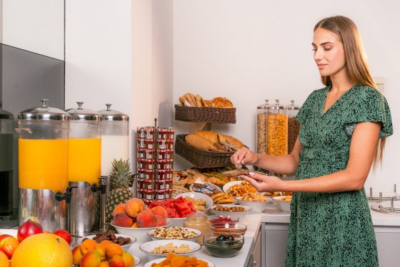 A lady serving herself breakfast from the buffet of fresh fruit, bread, jams and juices.